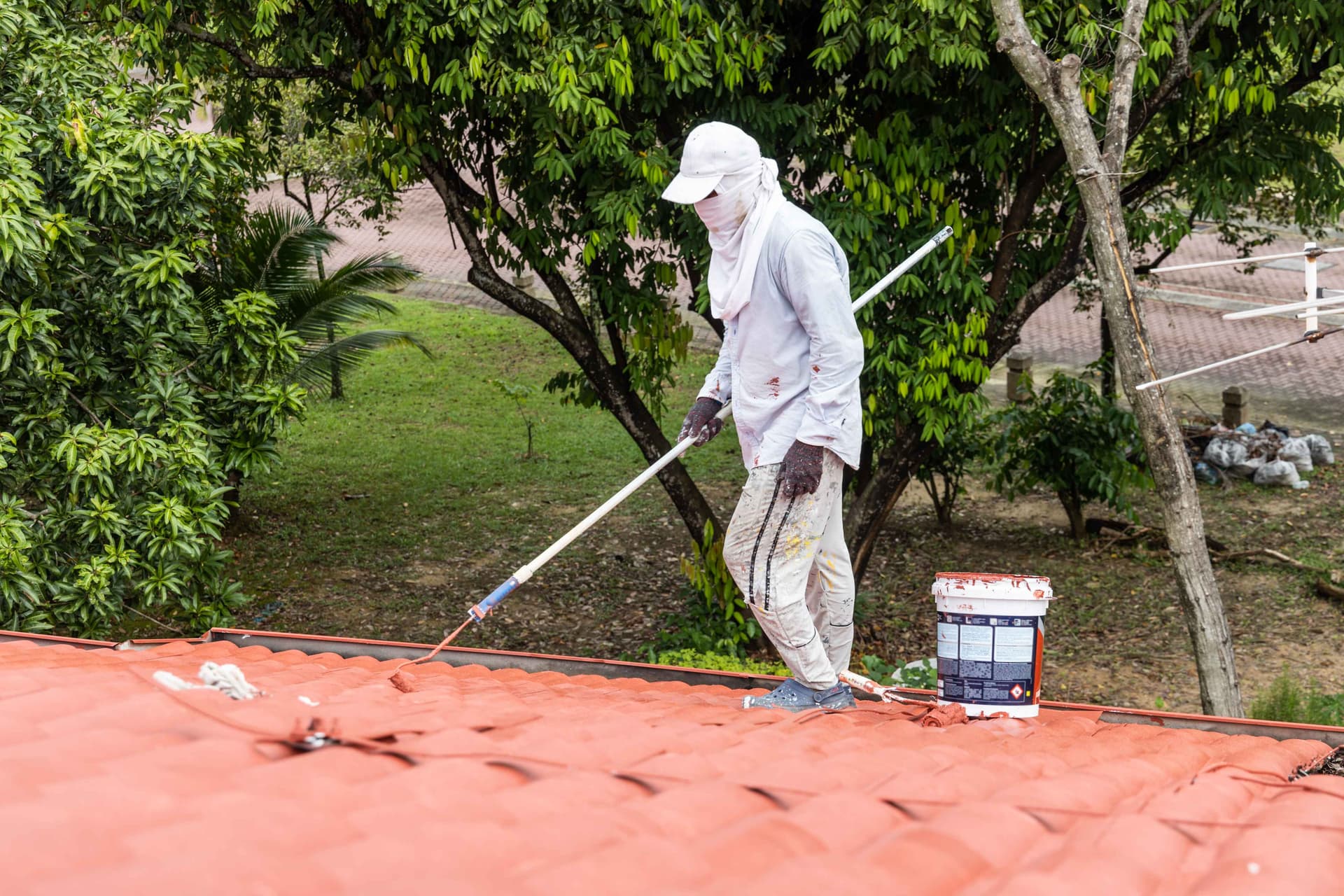 worker-painting-red-rooftop-with-roller-at-residen,jpg